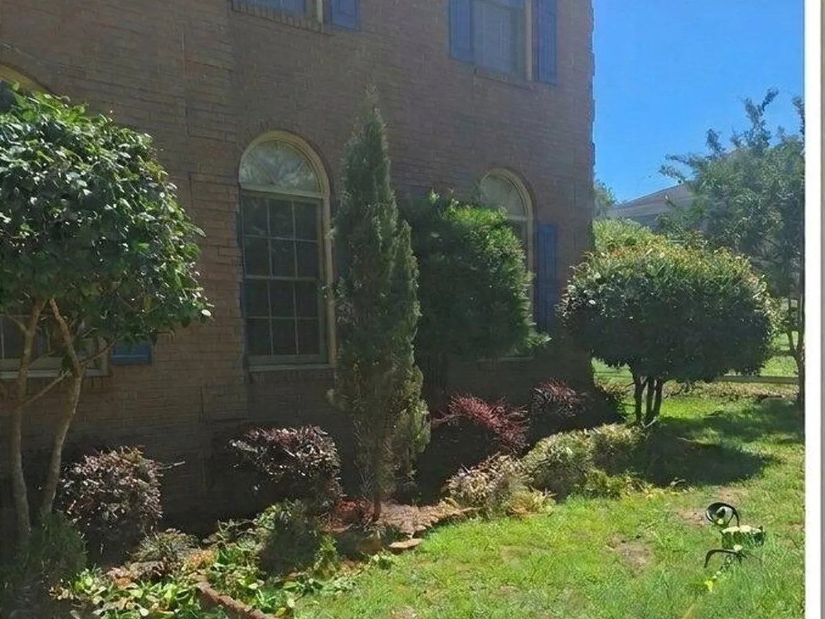 Two story brick home, front beds and lawn brought back, before