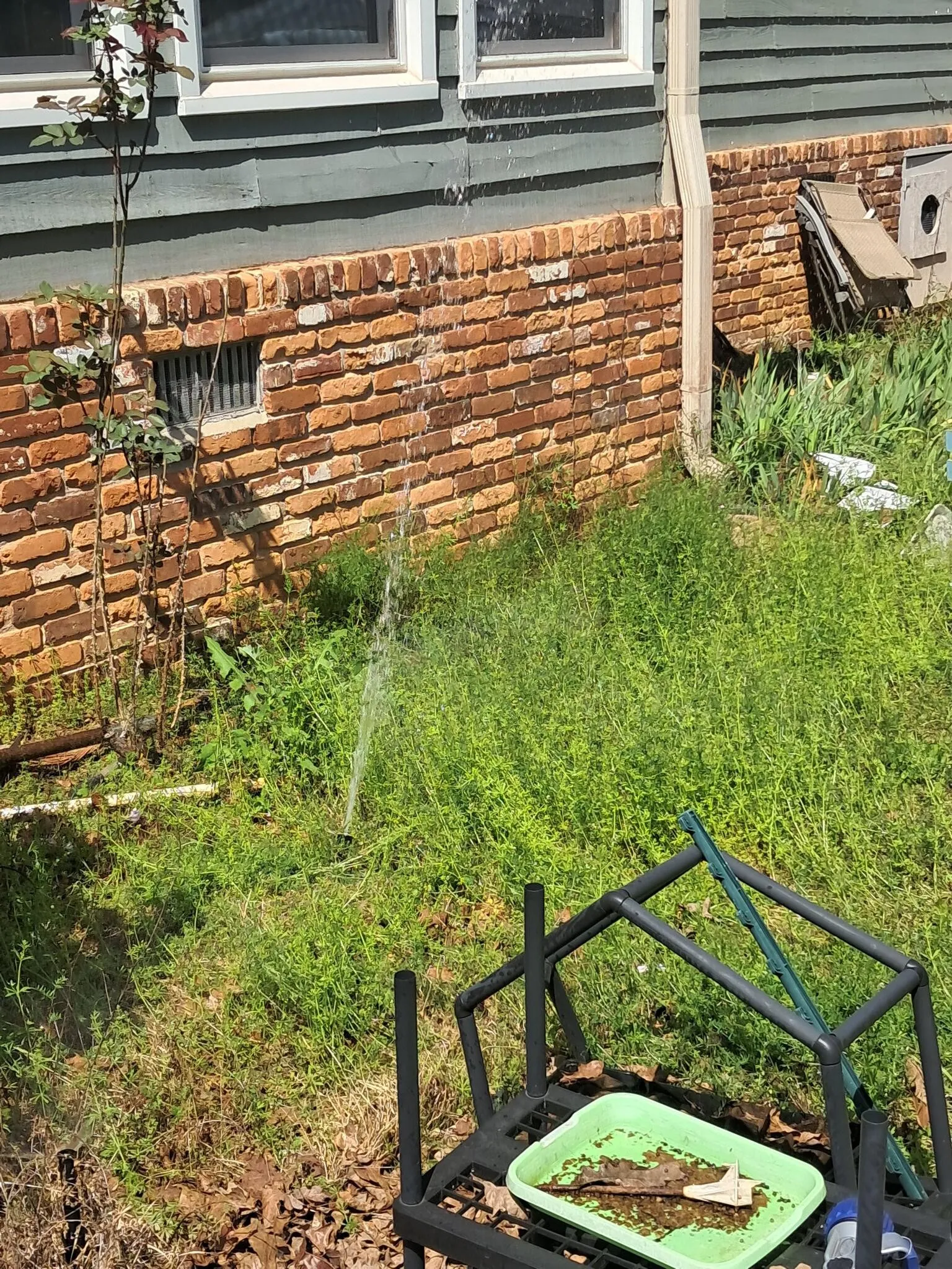 Downspout and drainage work along a brick foundation