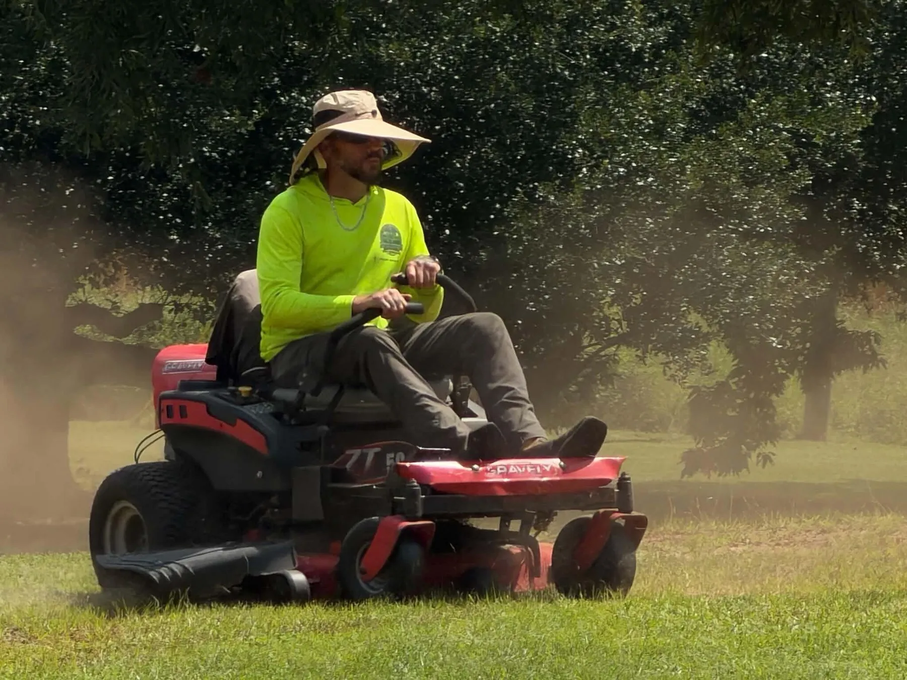 Jonathan Riddle mowing a wide lawn on a red zero-turn mower