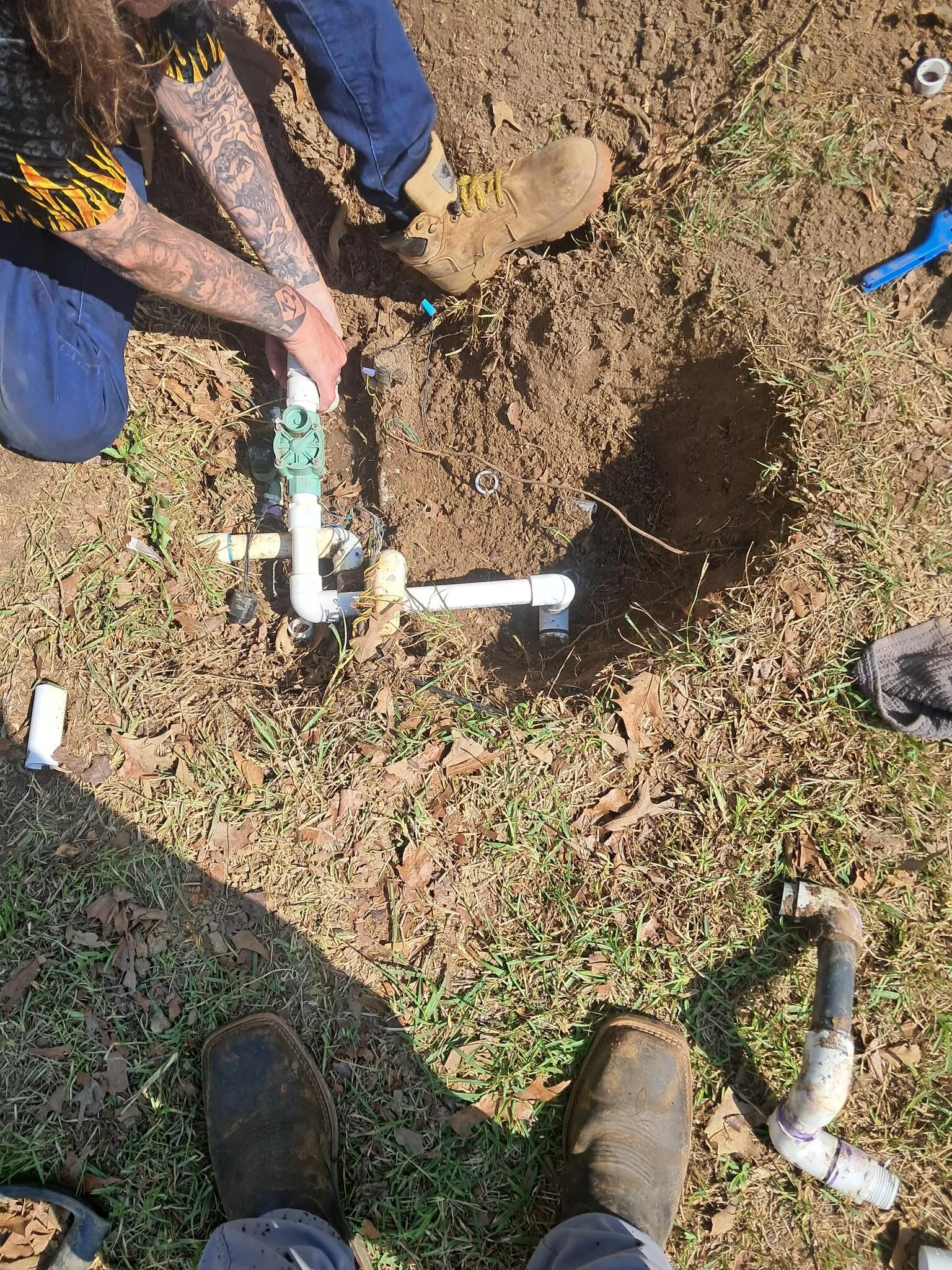 Gluing a new PVC fitting into an irrigation line in an open trench
