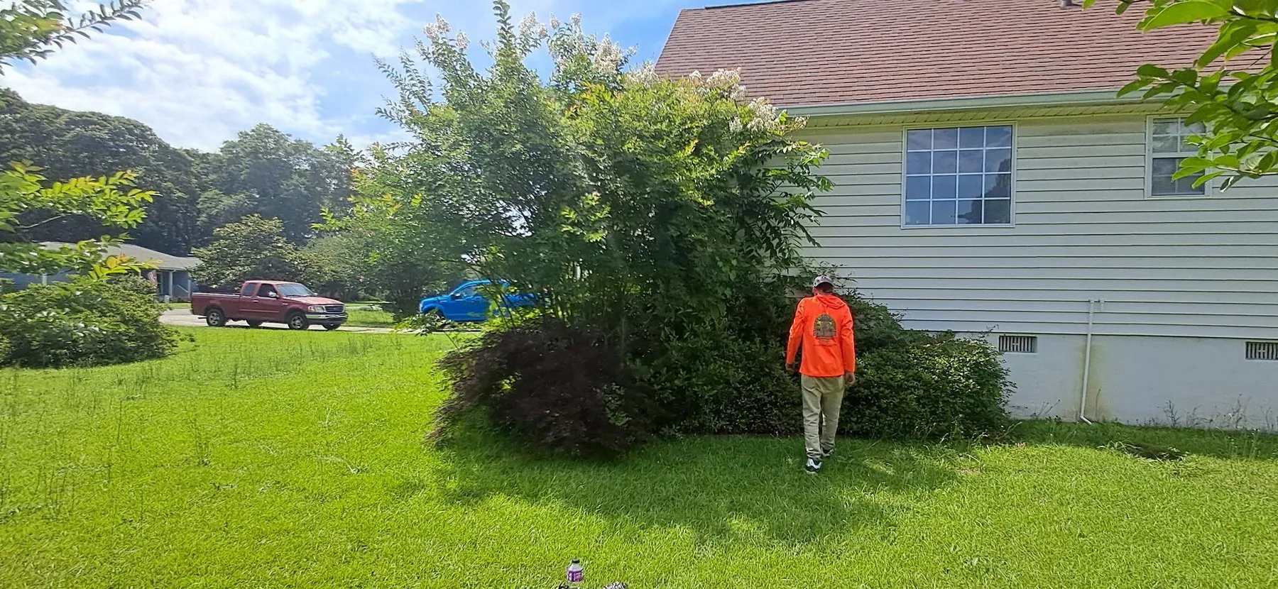 Trimming beds beside a home on a bright afternoon